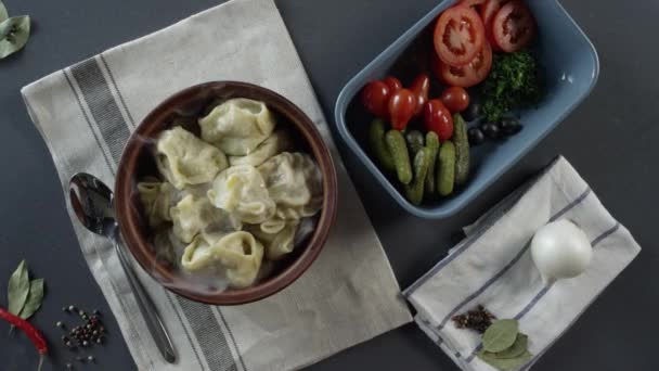 Close-up van de plaat met knoedels. Scène. Close-up van een plaat van knoedels. Bovenaanzicht van rustieke diner van knoedels en gesneden groenten op grijze tafel en bestek — Stockvideo