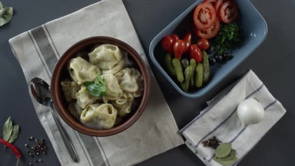 Close-up of plate with dumplings. Scene. close-up of a plate of dumplings. Top view of rustic dinner of dumplings and sliced vegetables on grey table and cutlery — Stock Video