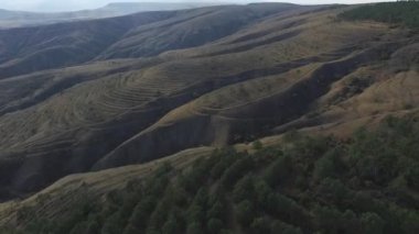 Dalgalı tepeler panorama, günbatımı zaman havadan görünümü. Vurdu. Dalgalı orman dağ manzarası, havadan görünümü. İhale gökyüzü renkler, parlak güneş ışığı. Kafkas Dağları doruklarına,