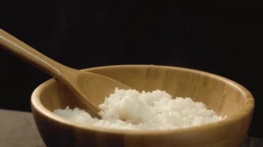 Yakın çekim sıcak pirinç ve tahta kaşık ile ahşap kase. İştah açıcı pirinç restoranda servis hazırdır