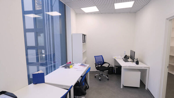 Small office view. Non-working time in office. Modern compact office room with several workstations and bright artificial light. Concept of office interior