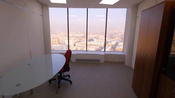 Widok z pokoju z panoramiczne okna na krajobraz miasta. Mały, przytulny pokój, stół, krzesło z szafa z panoramicznym oknem. Wnętrza pokoi na podróże służbowe pracowników — Zdjęcie stockowe