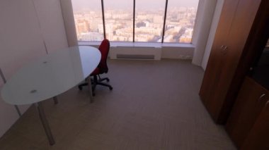 Şehir manzarası üzerinde Oda Panoramik penceresinden görünümü. Masa, sandalye ve dolap panoramik pencereli küçük rahat oda. İç odalar işçilerin iş gezileri için