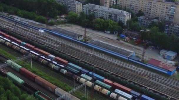 Top view of freight trains on railway tracks on background of houses. Footage. Import and export of freight transit by train — Stock Video