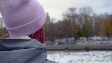 Arka görünüm sırt çantası şapkalı kadınla hipster close-up. Pembe saçlı ve sonbahar cityscape arka plan üzerinde pembe şapka genç güzel kadın