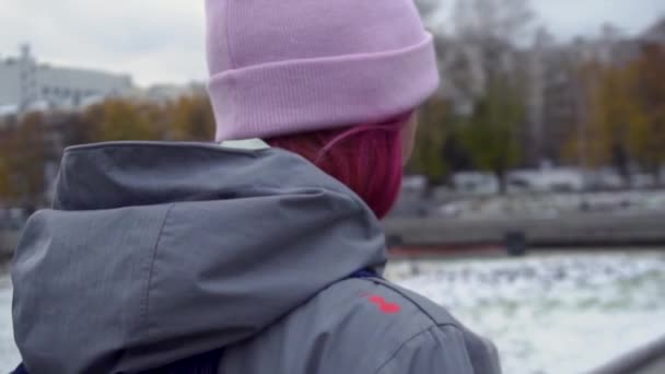Вид сзади на женщину-хипстера с рюкзаком в шляпе. Молодая красивая женщина с розовыми волосами и розовой шляпой на фоне городского пейзажа осенью — стоковое видео