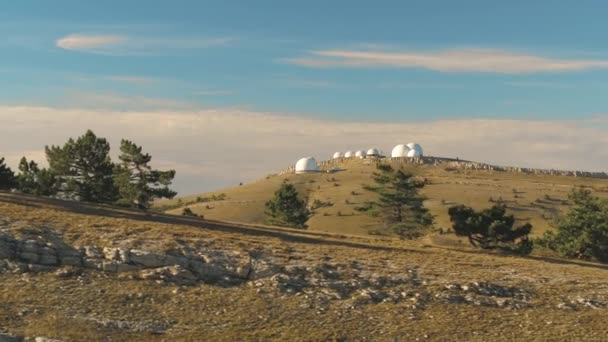 Top view of white domed buildings of observatories on hill. Shot. Astronomical research facilities and large observatories located at top with beautiful sunset sky and clouds — Stock Video