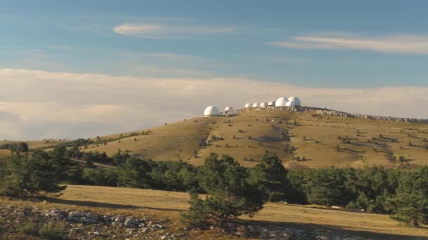 Vista superior de edifícios abobadados brancos de observatórios na colina. Atingido. Instalações de pesquisa astronômica e grandes observatórios localizados no topo com belo céu por do sol e nuvens — Vídeo de Stock