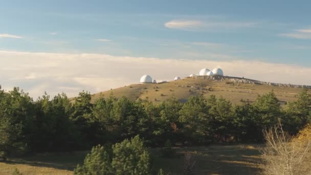 Vista superior de la cúpula blanca del observatorio en la cima de la colina. Le dispararon. Vista panorámica del complejo del observatorio astronómico en estado salvaje contra el cielo azul con nubes. Concepto de radioastronomía — Vídeos de Stock