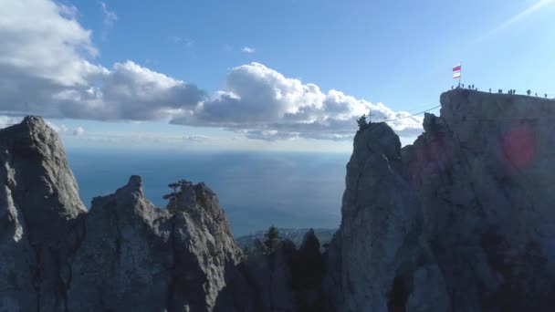 Amazing panorama of rock with rope bridge over precipice overlooking sea coast. Shot. Top view of rocks with rope bridges and many tourists climb it on clear day — Stock Video
