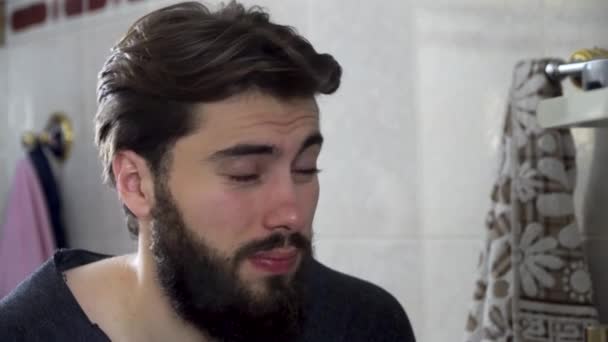 Kendisi de saçlarını yapıyor ve sabah hazır eve bir ev banyo aynada iç görünen genç genç adam portresi. Tıraşsız yakışıklı aynaya bakıyorum — Stok video