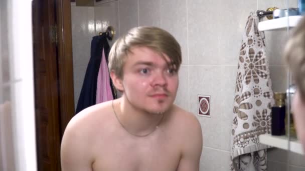 Mladý muž postřiku vodou na obličeji po holení, stříkající vodou na tváři. Muž, mytí obličeje s čistou vodou před zrcadlem v koupelně. Chlapec, mytí obličeje ráno — Stock video