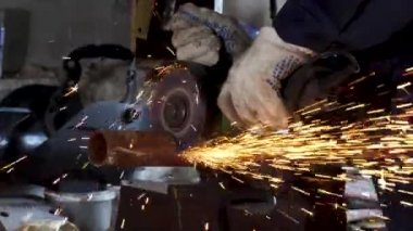 Erkek el nargile parçaları açısı öğütücü ile keser. Bir çelik inşaat alanında kıvılcım sıçraması ile kesme. Metal açılı taşlama kesim sırasında kıvılcım