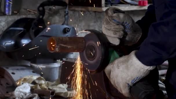 Mão masculina corta pedaços de tubo de água com moedor de ângulo. Corte de um aço com salpicos de faíscas no canteiro de obras. Faíscas durante o corte de moedor de ângulo de metal — Vídeo de Stock