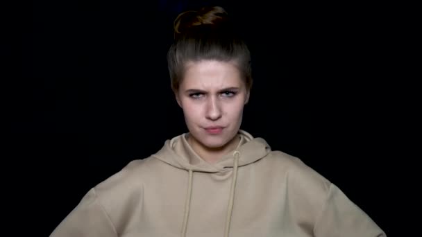 Young woman frowning over black background. Angry woman on black background with frowning face — Stock Video