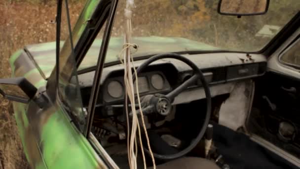 Acercamiento viejo coche verde oxidado en la textura de la hierba seca alta. Le dispararon. El interior del viejo coche de pasajeros destruido entre la hierba alta amarillo otoño en un día tranquilo . — Vídeos de Stock