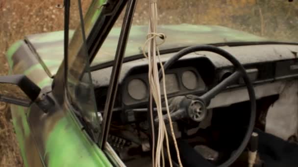 Fermer la vieille voiture verte rouillée dans la texture de l'herbe haute flétrie. Fusillade. L'intérieur de l'ancienne voiture détruite parmi les hautes herbes jaunes d'automne par une journée calme . — Video