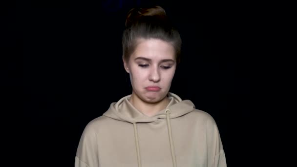 Portrait of a very sad and depressed young woman isolated on black background. Very sad, unhappy woman with childish expression on her face — Stock Video