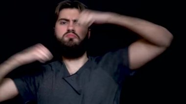 Genç siyah arka plan üzerinde müzik ve dans ederken izole hipster adam sakallı. Siyah arka plan üzerine eğleniyor gri süveterli çekici genç adam