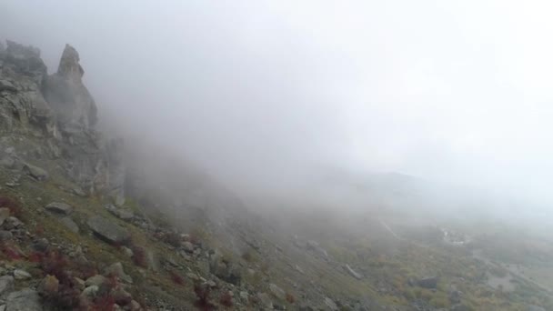 Lado rocoso de la montaña en la niebla. Le dispararon. Vista superior de las caídas de roca en la ladera de la montaña. Niebla densa envuelve roca en otoño día nublado — Vídeos de Stock