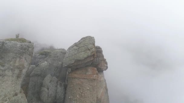 Panta muntelui în ceaţă. Împuşcat. Ceaţa gri densă învăluie întregul spaţiu. Vedere de sus a rocii care se scufundă în ceață rece de toamnă — Videoclip de stoc
