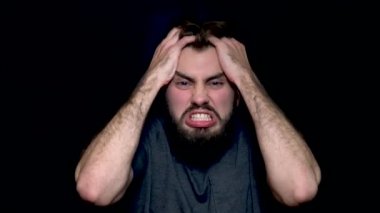 Kızgın genç adam bağırmaya, onun saç dışında yırtılma olumsuz duygular ifade siyah arka plan üzerine izole. Bağırıyor ve çığlık stresli bir genç adam yakın çekim