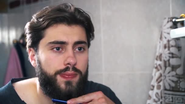Attraktiv man bryr sig om sitt skägg. Han är mycket koncentrerad — Stockvideo