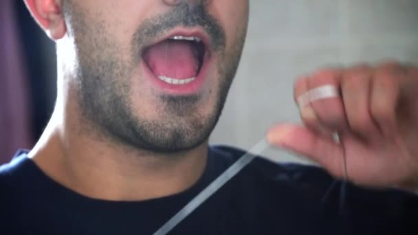 Close-up de homem sem barba segurando fio dental perto de seus dentes. Ele quer usar fio dental nos dentes. . — Vídeo de Stock