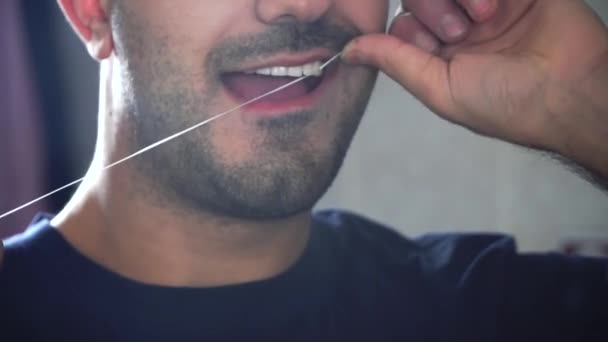 Крупный план человека, который чистит зубы зубной нитью. Стоматологическая помощь . — стоковое видео