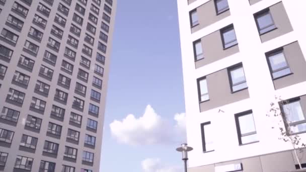 Vista inferior de edificios residenciales con cielo azul. Una trampa. Vista inferior de la fachada de la casa moderna de varios pisos — Vídeos de Stock