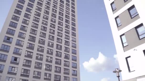 Pohled zdola obytných budov s modrou oblohou. Rám. Pohled zdola fasády moderní multi patrový dům — Stock video