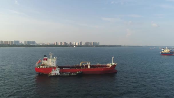 海岸沿いの海に浮かぶ赤い大きな船の空中。ショット。海はしけは、背景に他の船と物資を輸送します。. — ストック動画
