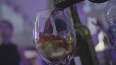 Ferahlatıcı sangria, yumruk meyve ve kırmızı şarap döktü yavaş cam içine. Çerçeve. Cam narenciye ile kırmızı şarap ile doldurulur.