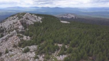 Üstten görünüm kaya turist. Küçük. Ufuk bulutlu gökyüzü ile tepelik arazinin. Kayalık vadi ve ağaçlar turistler arasında yürüyüş görünümü