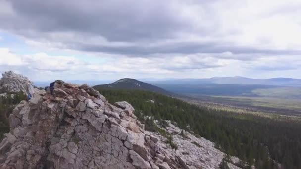観光客で岩の上から見る。クリップ。曇り空で起伏のある地形の地平線。岩の崖に登る観光客のビュー — ストック動画