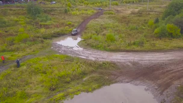 Blick auf Geländewagen, die in Pfützen fahren. Clip. Draufsicht auf Geländewagen, die bei Rennen in Schlammpfützen fahren. Offroad-Rennen in offenem Waldgebiet — Stockvideo