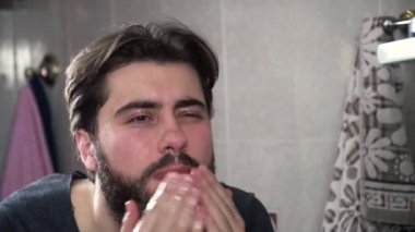 Adamın yüzünü su ile yıkama yakın çekim portre. Kalın sakallı adam banyoda yıkar. Sabah rutin çamaşır yüz