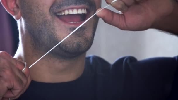 Il giovane con la barba usa il filo interdentale per pulirsi i denti. Primo piano di un uomo che usa il filo interdentale. Bocca assistenza sanitaria — Video Stock