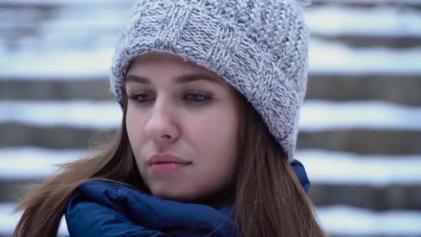 Mujer joven en invierno. Mirada pensativa de mujer hermosa en sombrero de invierno con sonrisa en su cara — Vídeos de Stock