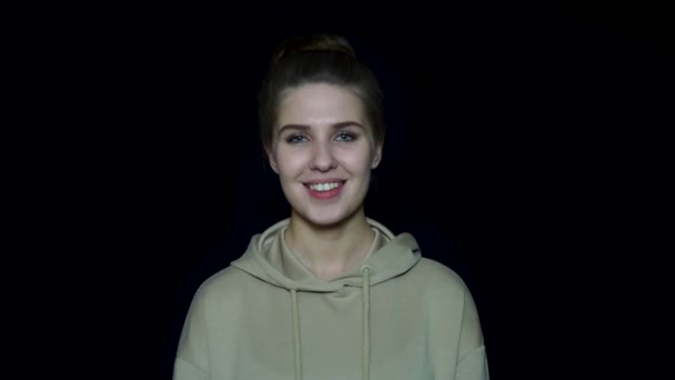 Kvinna isolerad på svart bakgrund. Vacker ung kvinna i tröja och hem frisyr leende på svart bakgrund — Stockvideo