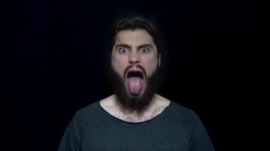 Sakal ve öfkeyle yapışkanlık dışarı dil olan genç adam. Kızgın genç adam açık ağız ile çılgınlığı'na. İnsan yüz ifadeleri ve duygular