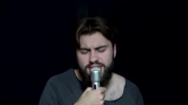 Sakallı mikrofona doğru söylüyor. Sakallı genç adam duygusal mikrofon şarkı söylüyor. Karaoke bar. Eğlence ve eğlence