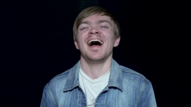 Lachender junger Mann. Netter Mann, der über lustigen Witz lacht. menschliche Mimik und Emotionen. schwarzer isolierter Hintergrund — Stockvideo
