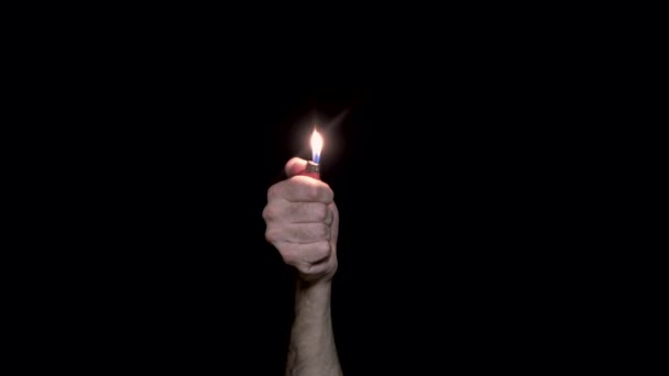 Närbild av mans hand lit lättare. Upplysta tändare på svart bakgrund. Ljus i mörka symbol för minne och solidaritet — Stockvideo