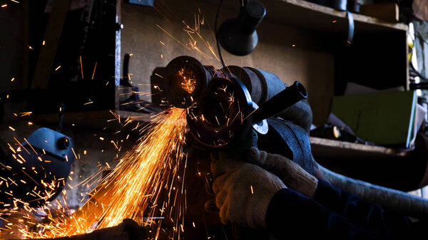Close-up of worker cutting metal with grinder. Frame. Sparks while grinding iron. Circular cutting disc cuts of metal