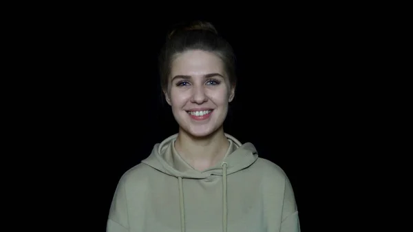 Femme isolée sur fond noir. Belle jeune femme en sweat-shirt et coiffure à la maison souriant sur fond noir — Photo