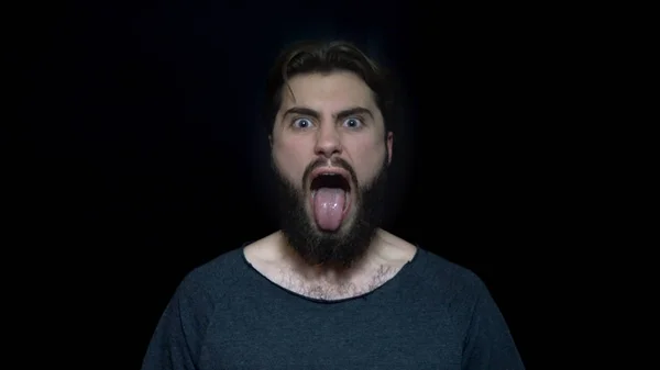 Fiatal férfi szakáll és a nyelv kilóg a düh. Mérges fiatalember, aki az őrület, nyitott szájjal. Emberi arc-kifejezések és érzelmek — Stock Fotó