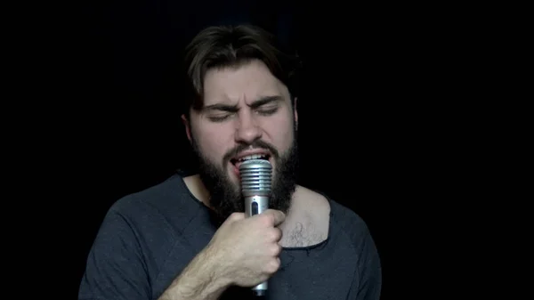 Man with beard sings into microphone. Young man with beard emotionally sings in microphone. Karaoke bar. Leisure and entertainment — Stock Photo, Image