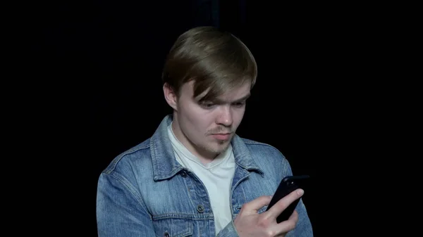 Le jeune homme regarde le téléphone. Un message est passé au téléphone. Homme au visage tendu regardant le téléphone — Photo