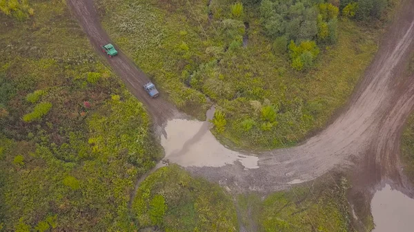 Blick auf Geländewagen, die auf Pfützen fahren. Clip. Blick von oben auf überwindende Pfützen von Geländewagen bei Matsch-Rennen. Jeep-Rennen — Stockfoto